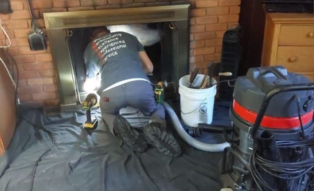 chimney sweep cleaning out a fireplace